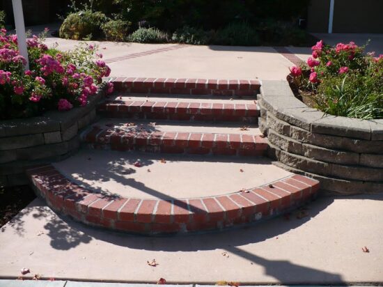 A brick staircase with flowers on the side of it.