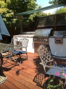 A patio with chairs and tables, grill and table.