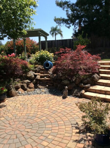 A garden with steps and rocks, plants and flowers.