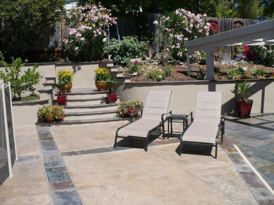 A patio with two lawn chairs and a table.