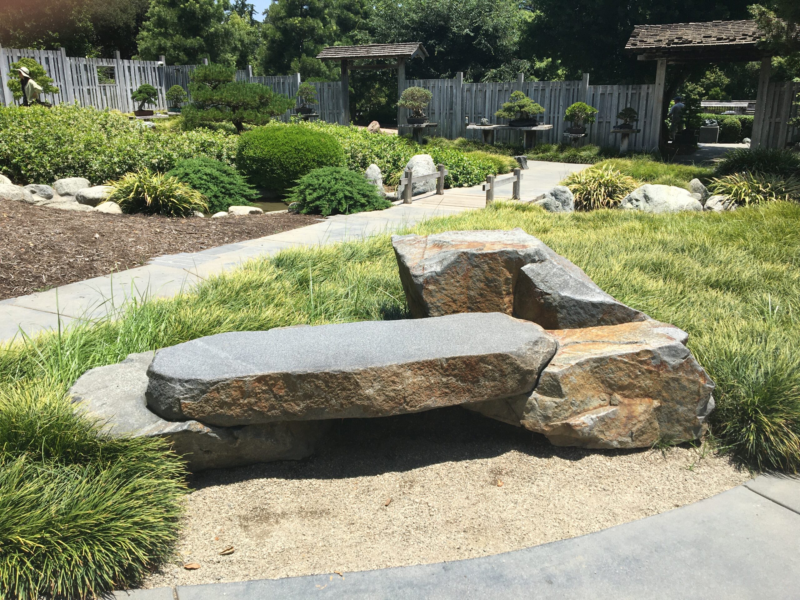 A stone bench in the middle of a garden.