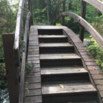 A wooden bridge with steps going over it. Stan Hywet Gardens