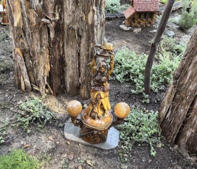 figure of a woman holding an unknown fruit aloft at Descanso Garden train area